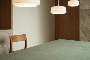 Masă de joc verde stilizată într-un studio neutru, cu lumină caldă și detalii discrete din lemn